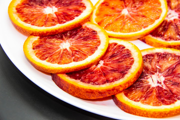 Sicilian sliced ​​orange on a white plate on a dark background. Sliced ripe Sicilian oranges...