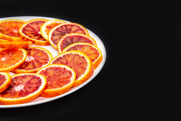 Sicilian sliced ​​orange on a white plate on a dark background. Sliced ripe Sicilian oranges...