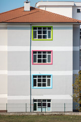 Grey building with red roof and colorful windows. School building for educational concept.