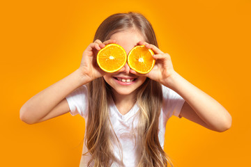 Funny little girl with citrus fruit on yellow background