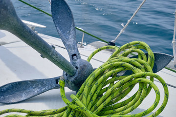 Close up Bow of the sail boat with anchor and light green rope. Sailing at summer sunny day. Yachting concept and sea background
