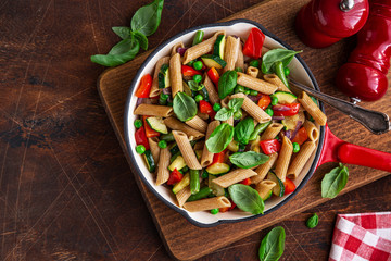 whole grain penne pasta with grilled vegetables ( zucchini, peas, bell pepper ant tomato) and cheese on pan