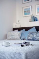 An open book and a Cup of hot coffee lie on the bed in the bedroom. Free time with an interesting book. Way of life, place for text