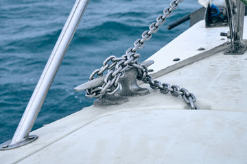 Bow of the sail boat with anchor and anchor chain. Sailing at summer foggy day. Yachting concept and sea background