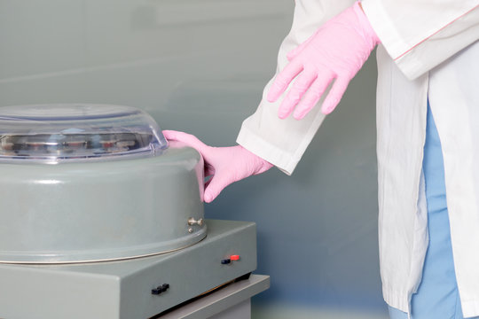 Hands of nurse are using centrifuge machine in medical lab.