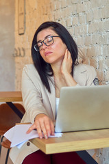 Headache, fatigue, stress in a young beautiful student girl studying online with a laptop.