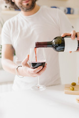man pours red wine into a glass