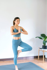 A young Asian woman practicing yoga indoors