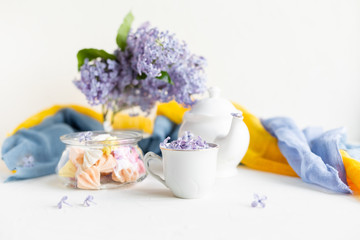 Fototapeta na wymiar Breakfast with black tea or coffee and meringue kisses on the white table. Spring lilac flowers in a glass vase.
