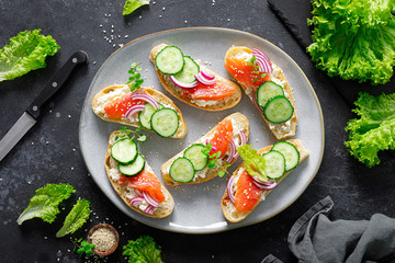 Fototapeta na wymiar Sandwiches with homemade ciabatta bread, salted salmon fish, feta cheese, cucumber, onion and fresh lettuce salad