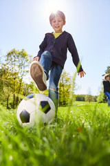 Naklejka premium Boy is playing with a soccer ball on a meadow