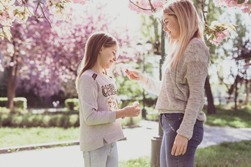 Sakura blossomed. Young mother with her child have fun in the park near the sakura. Spring morning. They look at each other