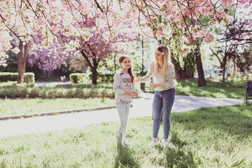 Sakura blossomed. Young mother with her child have fun in the park near the sakura. Spring morning. They look at each other