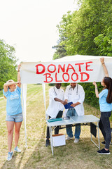 Freiwillige mit dem Plakat Donate Blood