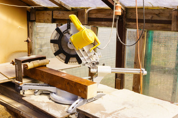 Miter saw in sawdust stands on a workbench after work.