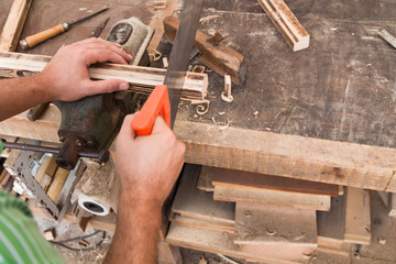 Male carpenter working on old wood in a retro vintage workshop.