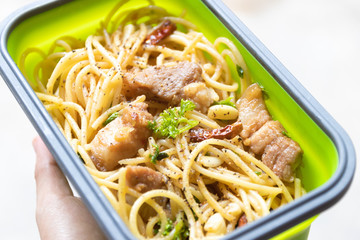 Spaghetti with belly pork, dried chili, garlic, olive oil and parsley. Homemade delicious and easy meal in take away microwaveable box on hand.