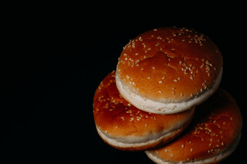 Three hamburger buns on a black background