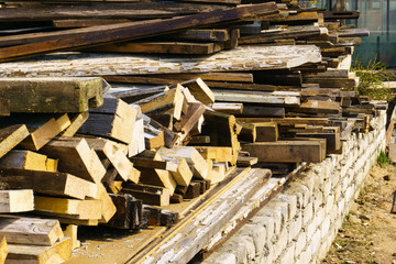 A pile of old boards lies on a brick foundation