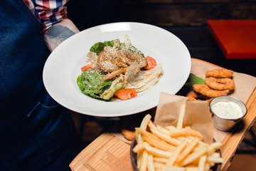 Cheese sticks in batter, French fries, salad with tomatoes, prawns, Basil and sesame, sauce on a white plate