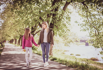 Obraz premium Young mother with baby walking in park near river. Spring morning. They look at each other