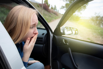 Fototapeta na wymiar Nausea during a car trip. A blonde woman suffers from kinetosis. The concept of motion sickness in diseases of the transport and vestibular apparatus