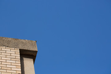 Upwards view of modern concrete buildings against a beautiful blue sky.
