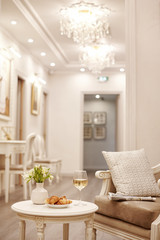 A glass of white wine, crispy croissants and a vase of white flowers sit on the table in the cozy living room