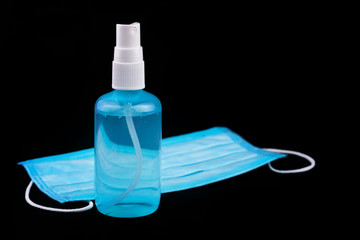 Medical mask and sanitizer on a black background. Antiseptic and protective disposable mask on...