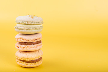Macaroons isolated on yellow background, floral and green leaves concept, summer or spring celebrations like Valentine's Day, Woman's Day, Mother's Day, March and Easter festive holidays