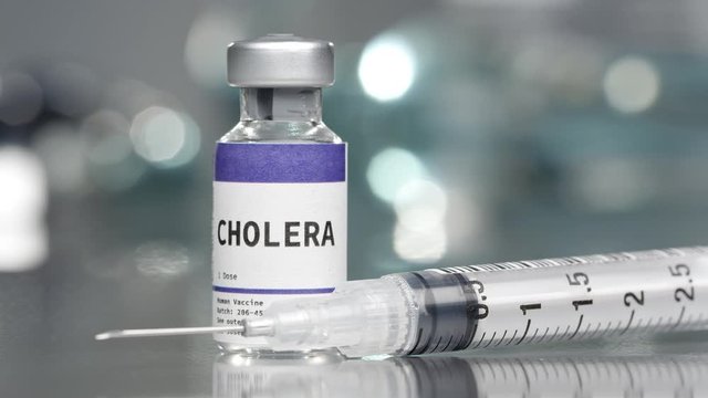 Cholera vaccine vial in medial lab with syringe placed next to it while it rotates.