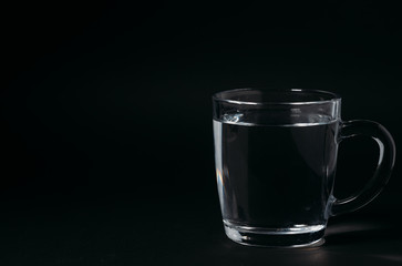 Glass with water on a black background. Cup of water.