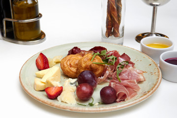 Close-up of a ready - made dish of meat, cheese and berries for a snack in a round plate on the table in a restaurant before dinner at a Banquet