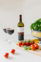 A bottle of red wine, two glasses, cherry, spaghetti and basil in the frame. Italian food concept.