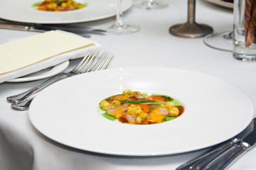 Close-up of a ready meal of meat, corn and sauce in a round plate on a white table in a restaurant before dinner at a Banquet