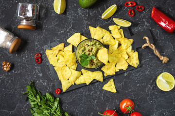 Nachos. Tortilla Chips with Guacamole on black stone background.