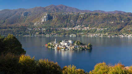 lake in the mountains in autumn with old buildong on an island in italy