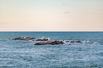 Fototapeta premium Mare e scogli frangiflutti con piccoli spruzzi di mare