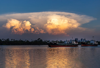 Two cargo ships parked in the middle of the Chao Phraya River and Dramatic sky background  in the evening.