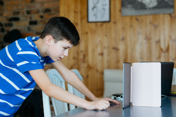 School kid using laptop while doing schoolwork at home. Homeschooling. School from home.