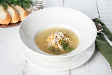 Chicken soup in a white rough plate served with bread