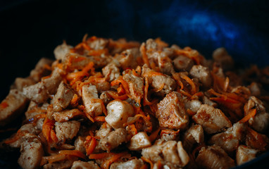 fried meat with onions and carrots in a pan