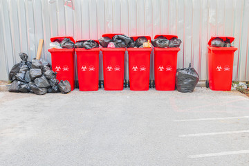 group red bins six with symbol infectious and  garbage bag black pile On top in the outdoors....