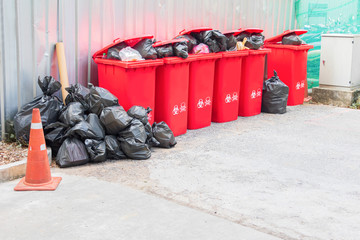 group red bins six with symbol infectious and  garbage bag black pile On top in the outdoors....
