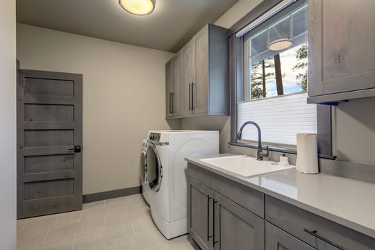 Beautiful Laundry Room With Rish Wooden Doors And White Washer And Dryer.