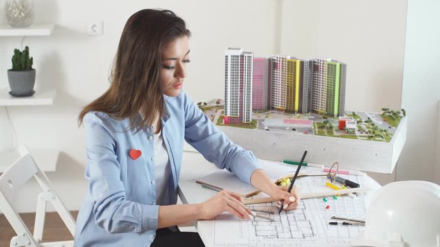 Confident satisfied smiling brunette woman creating new models of building. Renovation of commercial, institutional, industrial and residential buildings, girl designs landscape around buildings.