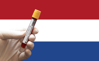 COVID-19 Pandemic Coronavirus concept ; Close-up of a Positive COVID-19 blood test sample tube with Flag of Netherlands at background. Blood testing for diagnosis new Corona virus infection.