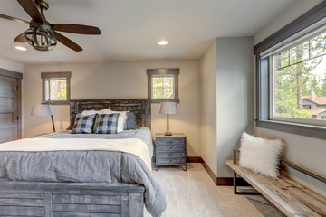 Natural tone luxury bedroom interiors in new American vacation home. Wood furniture and beige carpet.