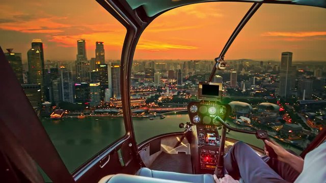 Helicopter cockpit interior flying on Singapore marina bay panorama of financial district skyscrapers at sunset on the harbor skyline. Aerial Singapore cityscape at twilight time.