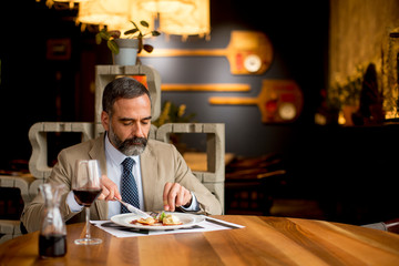 Handsome mature man drinking red wine during lunch